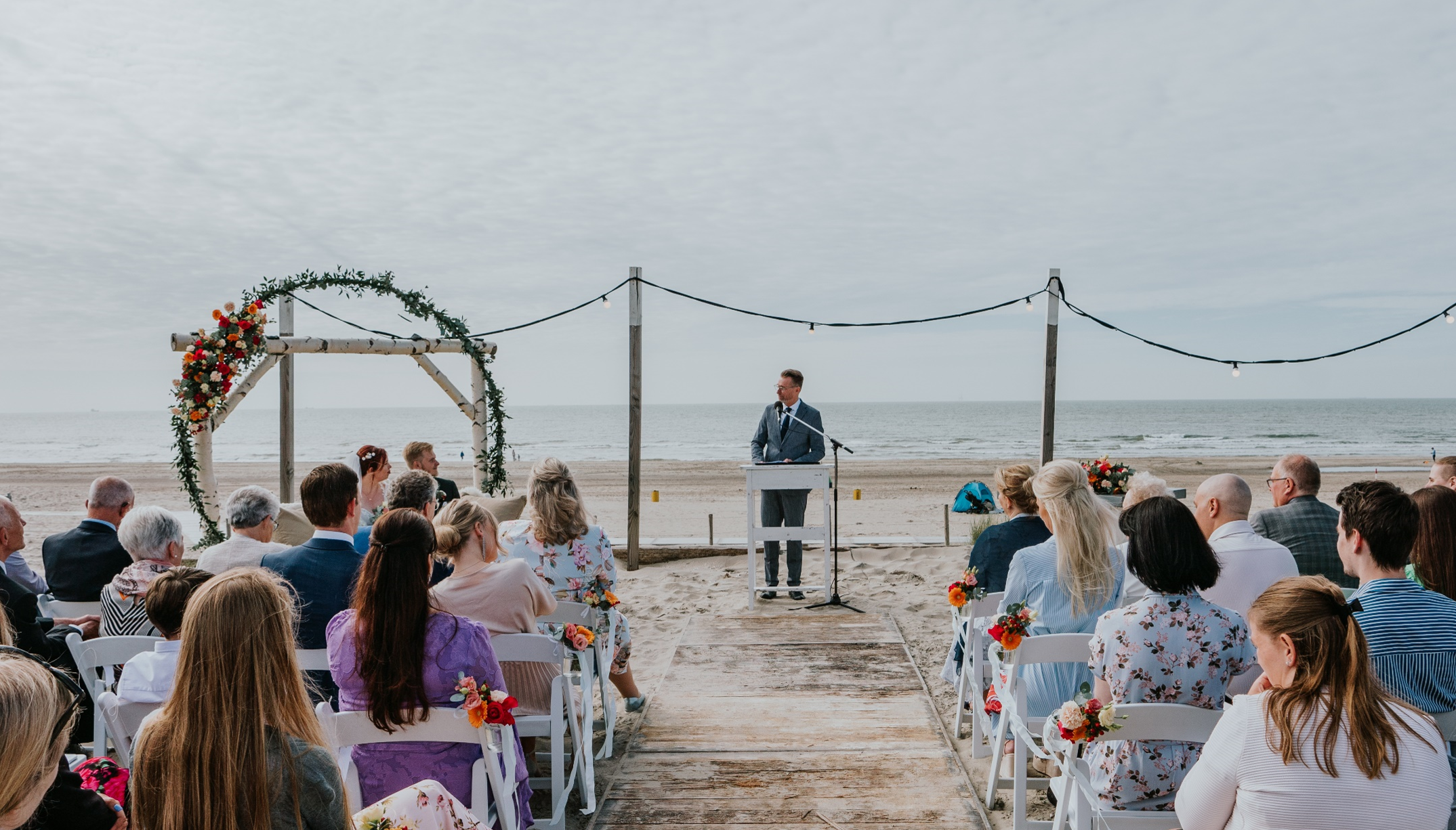 Meneer Herman Trouwambtenaar tijdens een ceremonie op het strand.